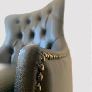 Detalhe do capitonê e do acabamento lateral do braço da Cadeira Martina MAVENA em courino preto